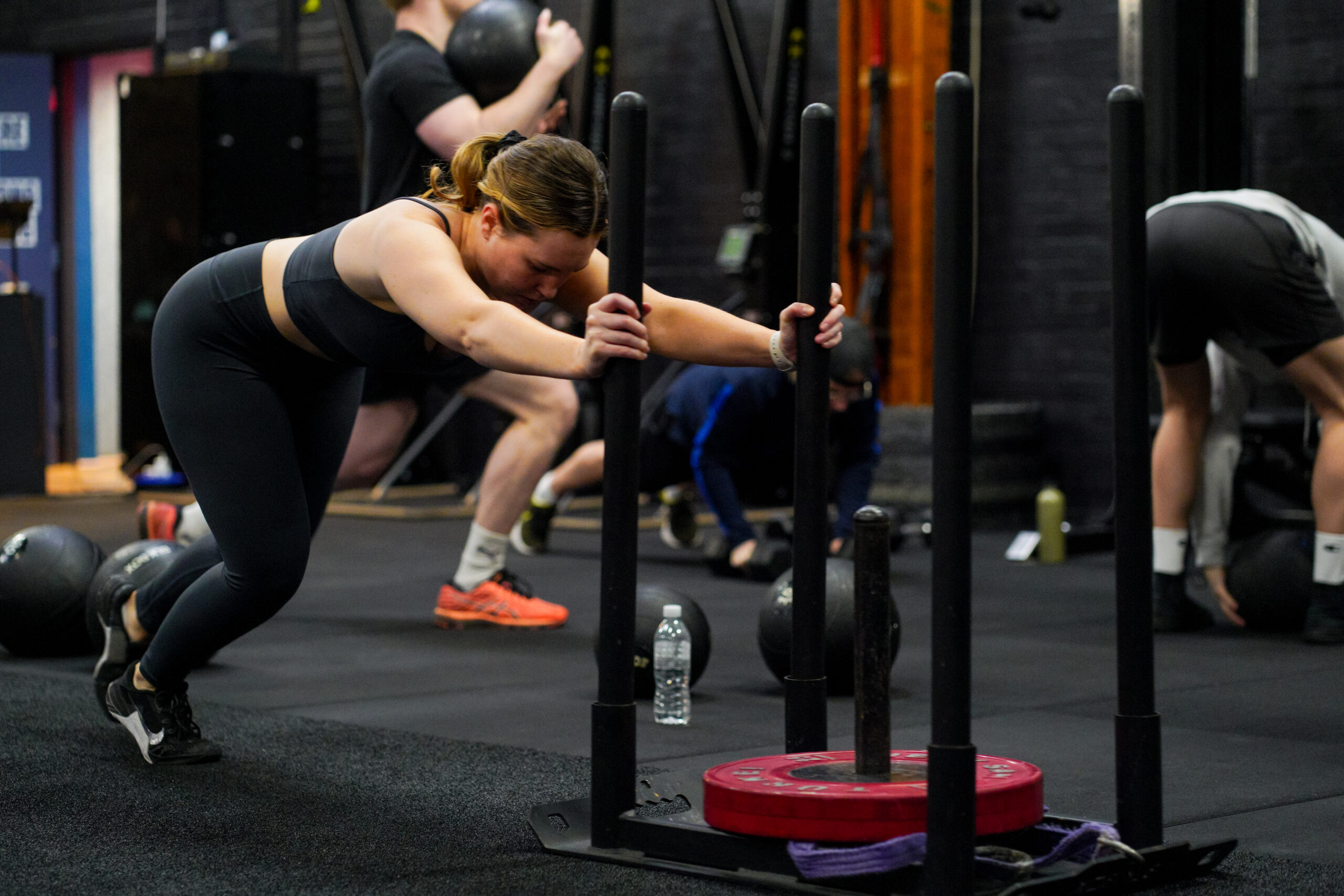 A member pushing a sled, coached